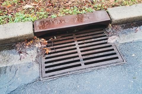 Metal storm drain with water running into it